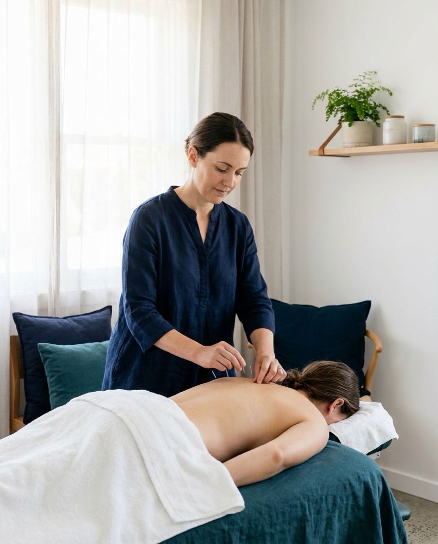 An acupuncturist treating a client in a quiet room